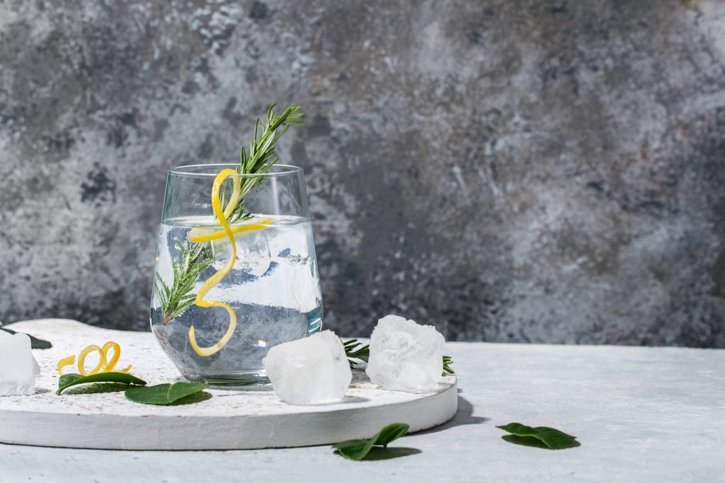 Gin and Tonic drink served with ice, lemon zest and fresh rosemary